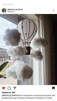 a hot air balloon hanging from the side of a window with clouds in front of it