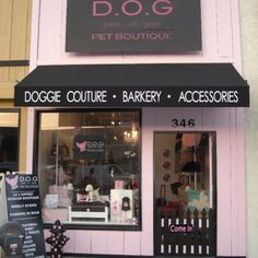 the dog boutique is located on the sidewalk in front of the building with pink trim