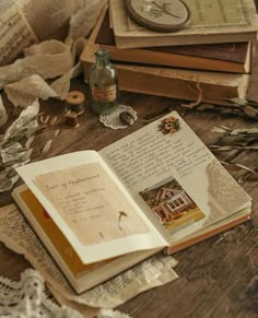 an open book sitting on top of a wooden table next to other books and papers