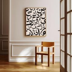 an abstract painting hangs on the wall next to a wooden chair in a white room