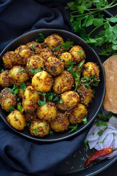 a black bowl filled with potatoes and herbs