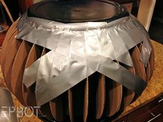 a large metal object sitting on top of a counter covered in duct tape and ribbon