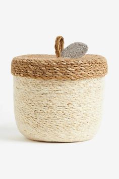 a white and brown basket with a leaf decoration on the top, sitting in front of a white background