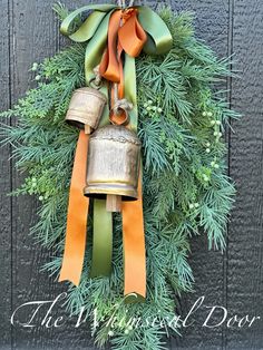 a christmas wreath with bells hanging from it's side and ribbon around the top