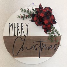 a merry christmas sign hanging on the side of a wall with a red and black bow