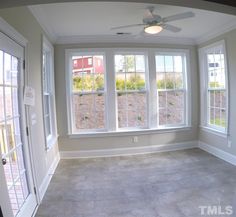 an empty room with three windows and a ceiling fan