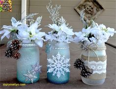 three mason jars filled with white flowers and pine cones