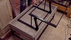 a person working on a table in a room that is being built with wood and metal