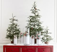 a red dresser with christmas trees on top and vases sitting on top of it