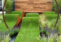 a wooden bench sitting in the middle of a lush green field with blue flowers and grass