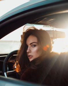 a woman sitting in the passenger seat of a car with sun shining on her face