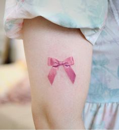 a woman with a pink bow tattoo on her arm