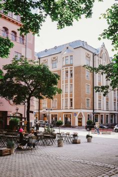 an empty square with tables and chairs in front of some buildings on the other side