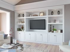 a living room filled with furniture and a flat screen tv on top of a white entertainment center