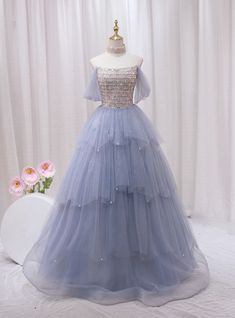 Admire this ethereal blue prom dress, a dream in tulle and sparkle! Fashioned to enchant, this gown features a shimmering, sequined bodice that catches every light, matched with an off-the-shoulder neckline that exudes elegance. The bodice seamlessly transitions into a multi-layered tulle skirt, adorned with delicate sparkles that mimic distant stars in the night sky. Each layer cascades in a gentle flurry, adding volume and a fairy-tale finish to this magnificent dress. Perfect for a prom or any special occasion, this dress guarantees you'll float through the evening with grace and poise. The soft blue hue complements every skin tone, ensuring that you look picture-perfect for every photo opportunity. Fairytale Dress Prom, Ethereal Blue, Gold Tulle, Photo Opportunity, Blue Prom Dress, Strapless Prom Dress, Prom Dress Plus Size, Layered Tulle Skirt, Marine Uniform