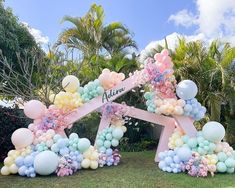 a bunch of balloons that are in the grass with some flowers on them and one balloon attached to it