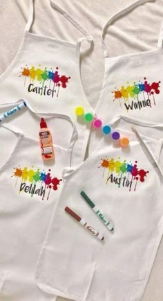 three children's aprons with paint and crayons on them, one for each child