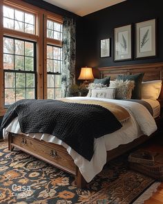 a large bed in a bedroom next to two windows with pictures on the wall above it