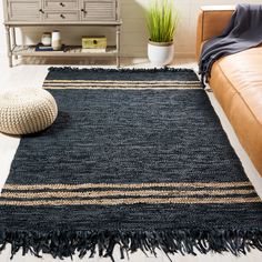 a living room with a brown couch and black rug on the floor in front of a white wall