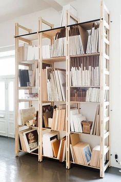 a bookshelf filled with lots of books on top of a hard wood floor