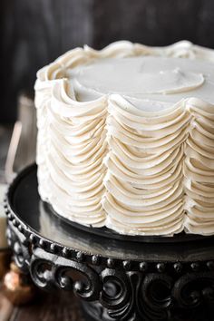 a white frosted cake sitting on top of a black plate