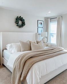 a large white bed sitting in a bedroom next to a window