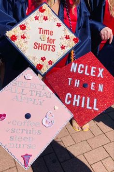 three graduates in caps and gowns hold up their graduation signs