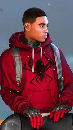 a young man in a red hoodie with spider - man hands on his chest