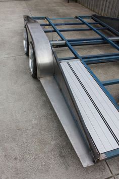 a flatbed trailer sitting on top of a cement floor next to a building with blue trim