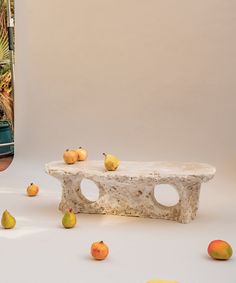 there are pears and oranges on the table next to an old stone bench