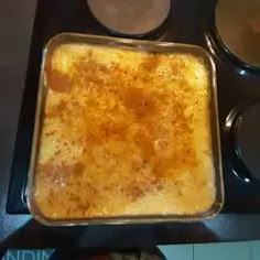 a casserole dish sitting on top of a stove next to two bowls of sauce