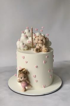 a white cake with pink hearts and teddy bears on the top, sitting on a plate