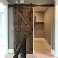 an open barn door in the middle of a room with wooden floors and railings