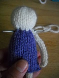 a hand holding a small knitted doll