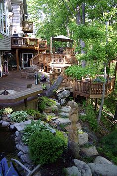 an outdoor deck and patio with steps leading up to the upper level, surrounded by greenery