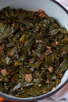 cooked collard greens in a white bowl on top of an orange napkin next to some carrots