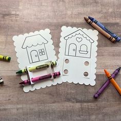 some crayons and markers are laying on the table next to two paper cutouts