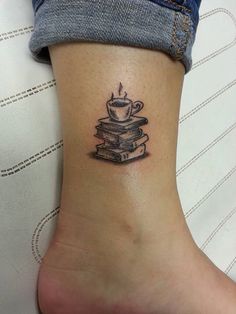 a tattoo on the ankle of a woman with books and a coffee cup in it