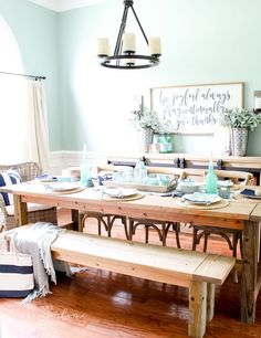 a dining room table set with place settings and plates on the wooden bench in front of it