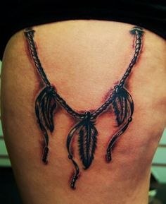 a woman's lower back tattoo with feathers and chains on her thigh, which is attached to an ankle