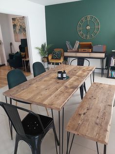 a wooden table sitting in the middle of a living room next to two green chairs