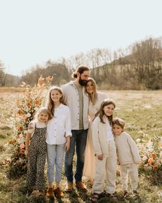 a man and two children are standing in front of a flower bush with orange flowers