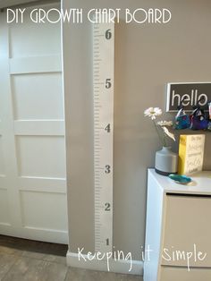 a tall growth chart in the corner of a room next to a dresser and door