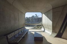 a long bench sitting in the middle of a cement tunnel with windows on both sides