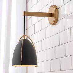 a black and gold light hanging from a white brick wall next to a shower curtain