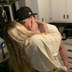 a man and woman hug in the kitchen while holding each other's neck around their shoulders