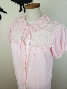 Description: Adorable 1950's/1960's light pink bed jacket. Features 5 buttons down the front and ties for a bow at the neckline with puff sleeves. Has a peter pan lace collar and detailing along the top of the bodice. Measurements Bust: 34/36 inches Waist: 36 inches Length: 36 inches Size suggestion (but please go by posted measurements): Small or Medium Condition: Good condition, seams along the lace at the neckline shown some wear. There is one large run on the back left hand side, shown in th Vintage Pink Sleepwear For Spring, Vintage Fitted Sleepwear For Sleepover, Vintage Pink Sleepwear, Fitted Vintage Sleepwear For Sleepover, Vintage Pink Sleepwear For Pajama Party, Retro Pink Sleepwear For Spring, Vintage Pink Sleepwear For Bedtime, Vintage Pink Sleepwear For Wedding, Vintage Pink Wedding Sleepwear