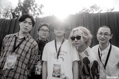 a group of young men standing next to each other in front of a wooden fence