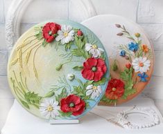 two plates with flowers painted on them sitting on a white shelf next to each other