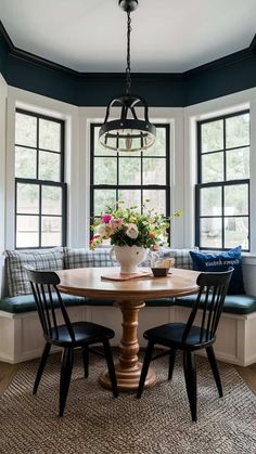 a dining room table with four chairs and a bench in front of two windows that have flowers on them